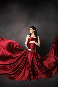 a woman in a red dress is posing with her long flowing fabric around her body