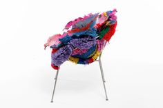 a chair covered in multicolored fabric and metal legs on an isolated white background