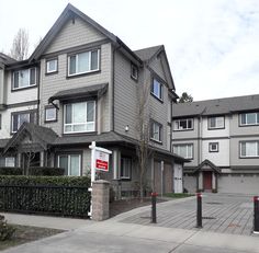 two story houses with garages on both sides and a for sale sign in front