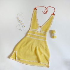 a knitted yellow dress next to a pair of white beads