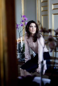 a woman sitting on the floor in front of a mirror with flowers and candles behind her