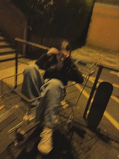 a man sitting on top of a shopping cart next to a metal fence and stairs