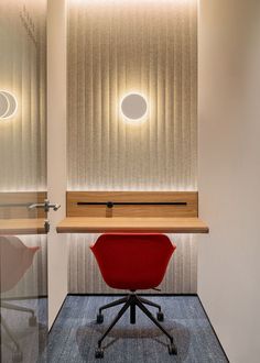 a red chair sitting in front of a desk with a light on top of it