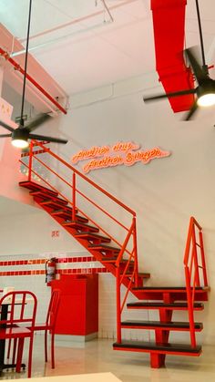 the interior of a restaurant with red chairs and stairs leading up to the second floor