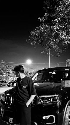 a black and white photo of a man standing next to a truck