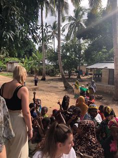 a group of people standing around each other in front of some palm trees and buildings