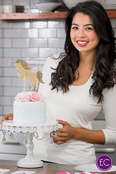 a woman standing in front of a cake on top of a white plate with pink frosting