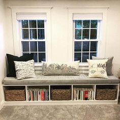 a room with two windows and some books on the shelf next to each other,