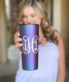 a woman holding up a purple and blue coffee cup with the letter h on it