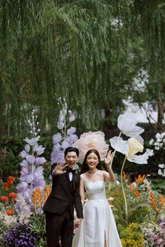 a man and woman in formal wear posing for the camera with flowers behind them on their wedding day