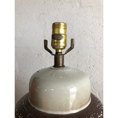 an old fashioned bell is sitting on top of a lamp shade that has been turned into a candle holder