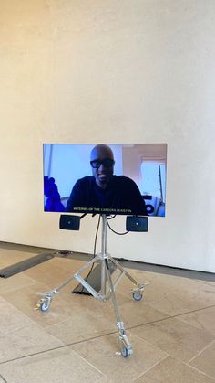 a man is on a video screen in the middle of an empty room with wheels