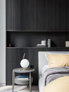 a bedroom with black and white striped wallpaper, a gray bed, two nightstands and a small round table