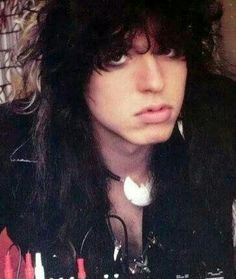 a man with long black hair and piercings on his head looking at the camera