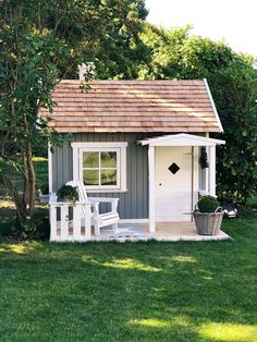 a small gray and white shed sitting in the grass