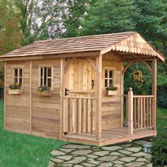 a small wooden shed sitting on top of a lush green field