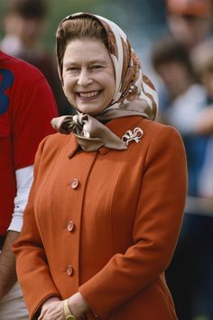 an older woman with a headscarf smiles as she stands next to other people