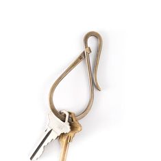 an old key hanging from a hook on a white wall