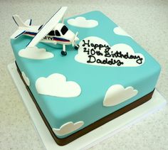 a birthday cake with an airplane and clouds on it