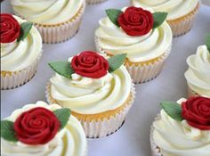 several cupcakes with white frosting and red roses on them are arranged in rows