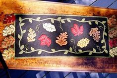 a rug with leaves on it hanging from the side of a wooden frame in front of a window