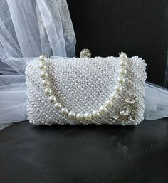 This exquisite White Pearl Evening Clutch Bag with Silver Hardware is the perfect accessory for any formal event. Whether you're a bride looking for the ultimate finishing touch or a bridesmaid wanting to add a touch of elegance to your ensemble, this stunning handbag is sure to make a statement. The lustrous white pearls and sleek silver hardware combine to create a timeless and sophisticated piece that will elevate your look. Add this versatile purse to your collection and shine bright at your Wedding Shoulder Bag With Pearl Handle, Rectangular, Pearl White Shoulder Bag For Wedding, White Handheld Shoulder Bag For Wedding, Elegant Pearl White Bag As A Gift, Pearl White Rectangular Formal Bag, Pearl White Rectangular Wedding Bag, Wedding Clutch Shoulder Bag With Pearl Handle, Pearl White Handheld Bags For Wedding, Elegant White Handheld Evening Bag