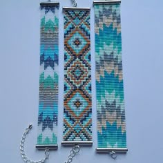 three pieces of beaded bracelets with chains attached to them on a blue background