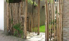 a wooden gate made out of sticks and vines on the side of a brick building