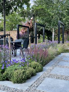 an outdoor garden with purple flowers and plants in the foreground, surrounded by stone walkways