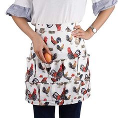 a woman wearing an apron with roosters on it and holding an egg in her hand