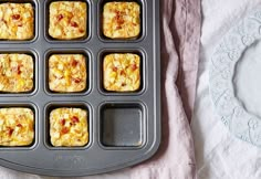 muffin tins filled with breakfast food on top of a pink napkin next to a white plate