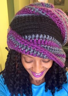 a woman with curly hair wearing a crochet hat and smiling at the camera