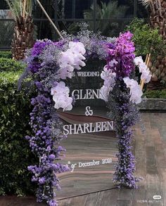 a wedding sign with purple flowers and greenery