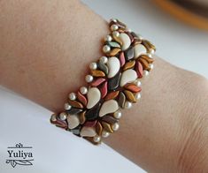 a close up of a person's arm wearing a bracelet with shells on it