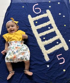 a baby laying on top of a blue blanket with the number five written in it