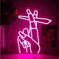 a pink neon sign with a hand holding a woman's head in the middle