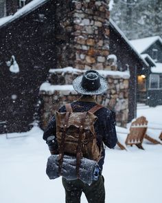 a man walking in the snow with a backpack on his back and hat over his head