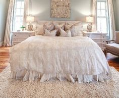 a large white bed sitting under a chandelier in a bedroom