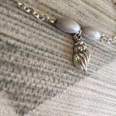 If you love spending your summer days at the beach, this fun summer seashell charm bracelet, with the cute conch shell charm and silver grey beads will be a wonderful reminder of happy days spent among the seashells. The delicate beach themed silver plated chain is light and small enough to wear on a daily basis, and will look great layered with other bracelets. Click here for more bracelet designs to layer up for a fun summer style! It would make a fun seaside gift idea for anyone you know who Beach Jewelry With Silver Pearl Charm, Beach Jewelry: Silver With Pearl Charm, Silver Beach Jewelry With Pearl Charm, Beach Silver Jewelry With Pearl Charm, Silver Dainty Bracelets For Beach, Dainty Silver Bracelets For The Beach, Silver Jewelry With Pearl Charm For Beach, Beachy Silver Strand Jewelry, Adjustable Silver Charm Bracelet With Starfish