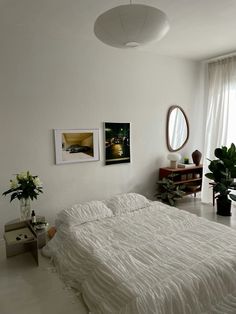 a white bed sitting in a bedroom next to a window with pictures on the wall