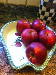 some red apples are in a bowl on the counter