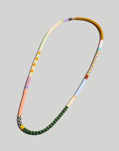 a multicolored beaded necklace on a gray background with an orange, yellow, and green cord