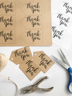 some paper tags that are on top of a table with scissors and yarn next to them