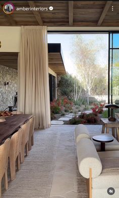 a living room filled with furniture next to a large glass window covered in white curtains