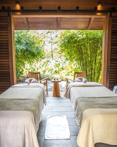 two beds in a room with wooden walls and doors leading to an outside patio area