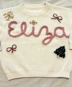 an ugly sweater with the word eena written on it and bows around the neck