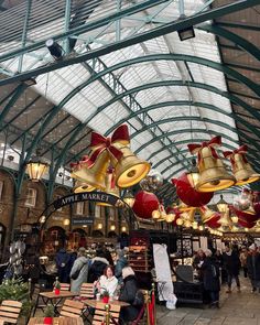 an indoor market with lots of tables and lights hanging from it's ceilings