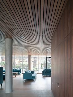 a living room filled with blue couches and wooden ceilinging on top of a hard wood floor