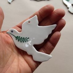 a hand holding a white ceramic bird ornament