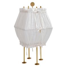 a white lamp shade with gold poles on it